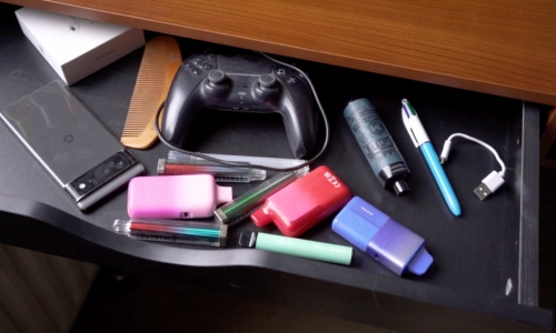 a close up of an open desk drawer with a few single use vapes inside