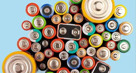 Top shot of collection of various domestic batteries, cutout on blue background