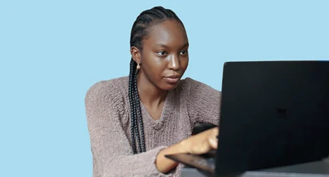 Photo shows a dark skinned woman learning online with a laptop, cutout on blue background