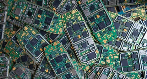 Top shot of a pile of mobile phone circuit boards, cutout on blue background