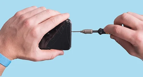 Photo shows pale skinned hands repairing a mobile phone, cutout on blue background