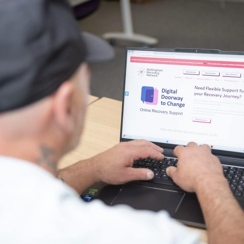 A white man sat at a laptop reading about Nottingham's tech donation project