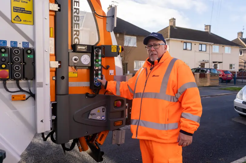 Ian, a bin lorry loader for Suez holding a button that loads the bins into the lorry